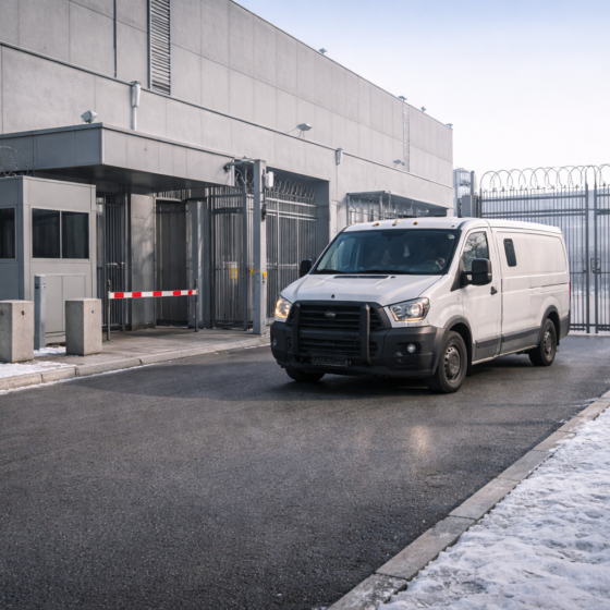 Secure financial operations facility exterior with an unbranded armored cash transport van arriving in winter daylight, no text